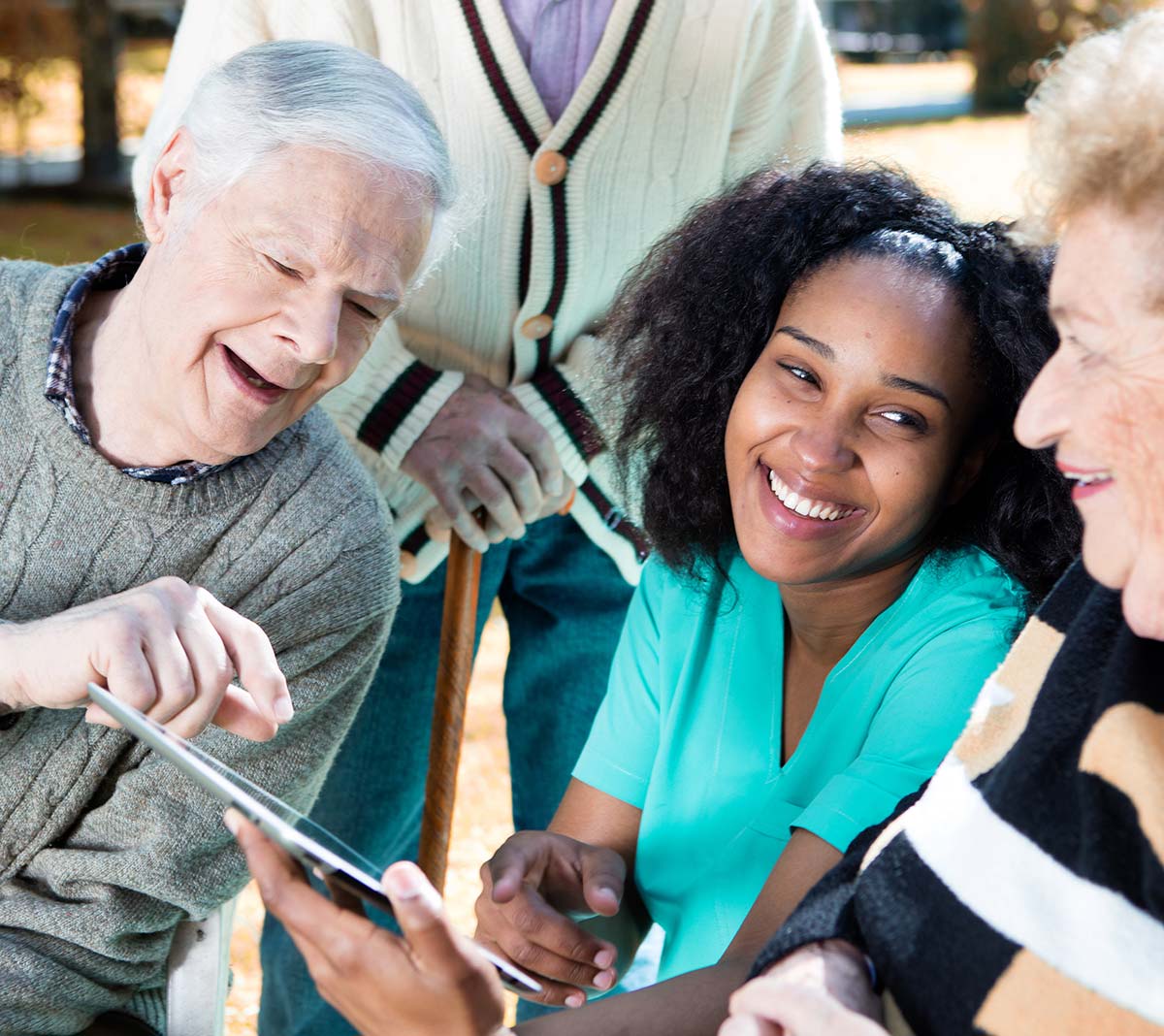 Nurse explaining use of tablet to senior people